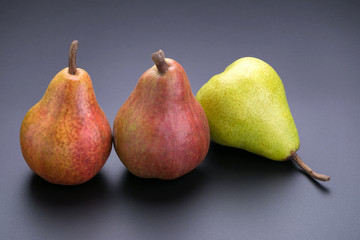 Ripe green and red pears on a black background
