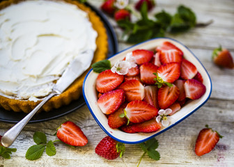 Delicious sponge cake with fresh strawberries and mascarpone on a wooden background.