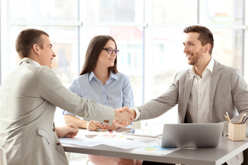 Businessmen shaking hands in office © Africa Studio