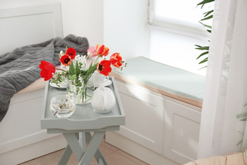 Fototapeta na wymiar Vase with beautiful flowers and tea set on table in modern veranda interior