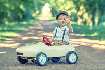 winkender Junge im Tretauto