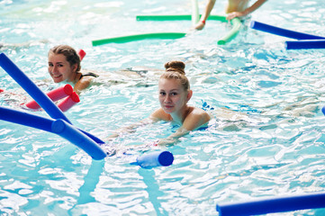 Fitness group of girls doing aerobical excercises in swimming pool at aqua park. Sport and leisure...