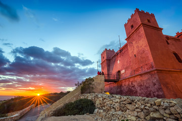 Il-Mellieha, Malta - Tourists watching sunset at St Agatha's Red Tower with beautiful sky and clouds
