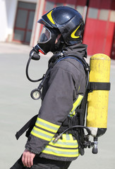 Fototapeta premium Firefighter with large yellow oxygen cylinder and protective hel