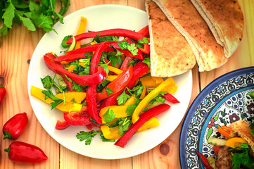 fresh vegetarian salad made with Bulgarian pepper and herbs. Wooden background. Top view. Close-up