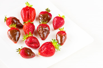 Strawberries dipped in delicious chocolate in white dish isolated on white background. Close up view.