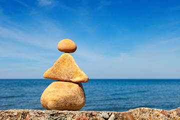 Yellow stones balance on a background of blue sky and sea