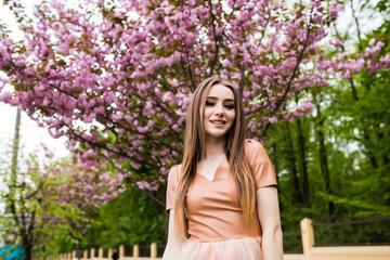 Naklejka premium Spring beauty girl near Blooming sakura tree. Romantic young woman portrait