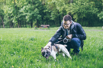 man iron a french bulldog in city park