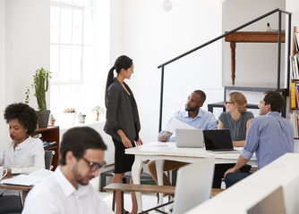 Woman talking with colleagues at a desk in open plan office