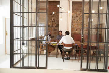 Three young men at a meeting in a boardroom