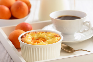 Homemade cheesecake with apricots on white wooden tray.