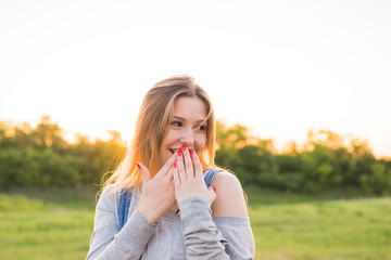 Fototapeta premium Surprised young woman covering her mouth with hands outdoors
