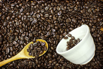 Coffee cup and coffee beans with wooden spoon on wooden table.