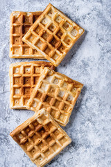 Empty homemade square belgian waffles over gray texture background. Top view with space
