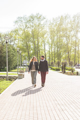 Stylish pregnancy concept - portrait of couple of hipsters husband and wife in trendy clothes walking in the city park