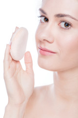 Young beautiful woman applying powder on her skin.
