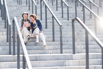 Obraz na płótnie Canvas Positive girl and boy sitting on steps with smile