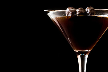 Black Manhattan Cocktail with olives on dark wooden surface.