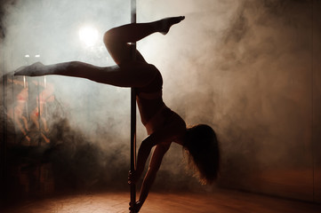 Fototapeta na wymiar young hot woman in sexy lingerie performs sensual pole dance. Go-go dancer