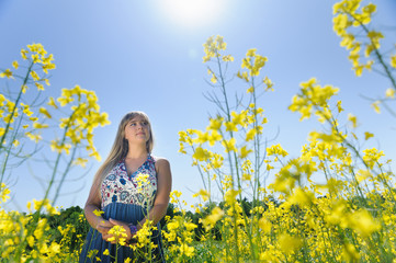 Fototapeta premium Cute woman in a yellow flowers field