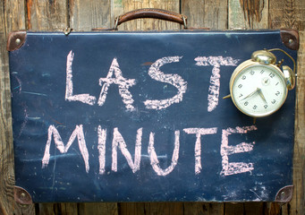 Last minute travel concept with old retro suitcase and alarm clock
