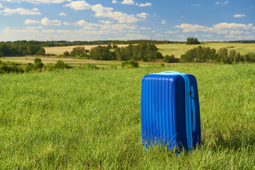 Obraz premium Blue suitcase on the meadow. Commercial shot. 