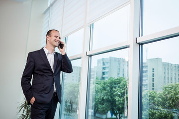 A businessman talking on a mobile phone,Businessman talking on the phone in office,Senior businessman,Portrait of businessman talking on mobile phone,business concept