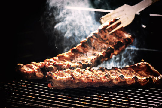Spare ribs cooking on barbecue grill for summer outdoor party. Food background