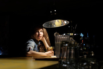 redhead girl sitting in bar (pub) drinking icy cocktail alone, looking for a company