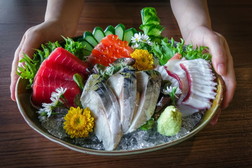 Hand holding  dish of Japanese sashimi seafood set