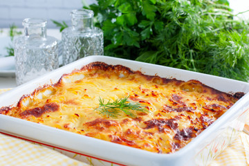 Potato casserole with ruddy crust on white table, selective focus, horizontal