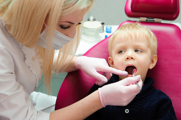 female dentist examines the teeth of the patient child. child mouth wide open in the dentist's chair