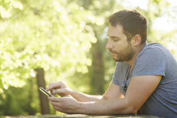 Naklejka na ściany i meble Man using smartphone in nature.