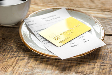coffee and receipt bill for payment by credit card on wooden table background