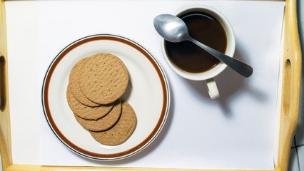 Brown biscuits in dish pairing with black coffee with teaspoon
