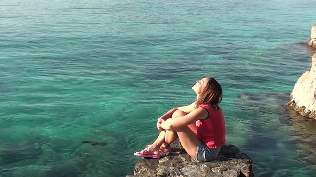 Woman at the seaside exposes face to the sun, squids in the water