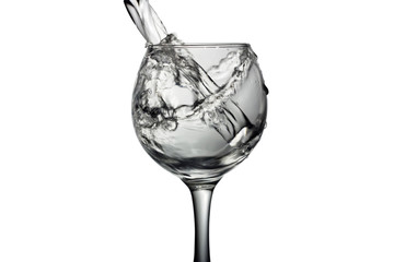 Water pours into a glass on a white background, monochrome image