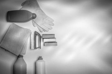 Range of cleaning products for the kitchen and bath. Detergents, chemical bottles, cleaning sponges and gloves. On a wooden table. view from above. Black and white filter.