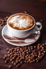 white cup of cappuccino on an old wooden table, coffee beans scattered on the table
