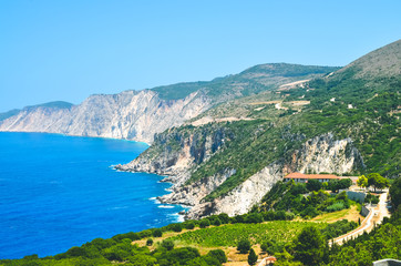 Fototapeta na wymiar Cephalonia shore cliffs and blue coastal sea waters. Olive plantage in foreground