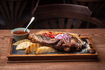 big fat fried steak on a wooden board with onions and fried potatoes with Bachall red wine, a nice feed at restaurant