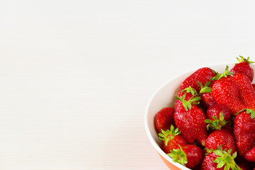 Red fresh strawberries in a bowl isolated on white background. Close up view.