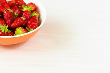 Red fresh strawberries in a bowl isolated on white background. Close up view.