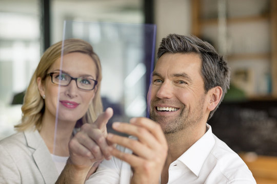 Smiling businessman and woman using futuristic portable device