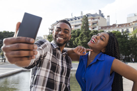 Portrait of happy young couple taking selfie with cell phone