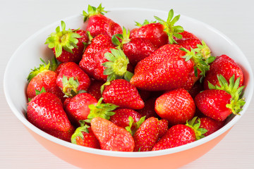 Red fresh strawberries in a bowl isolated on white background. Close up view.