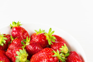 Red fresh strawberries in a bowl isolated on white background. Close up view.