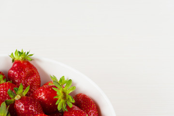 Red fresh strawberries in a bowl isolated on white background. Close up view.