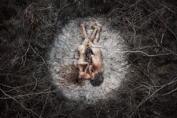 Beautiful naked man and woman lying on dry crack ground in fetal position. Environment and ecology concept. Top View